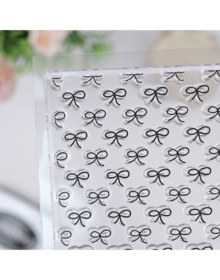 Placa transparente com padrão repetido de laços em relevo.