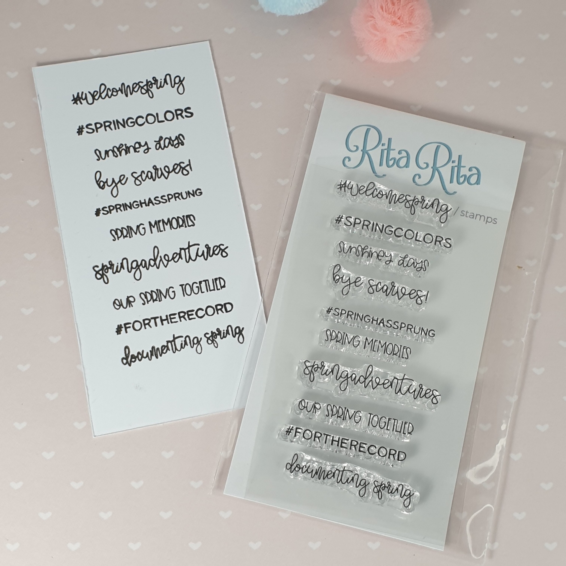 Dois conjuntos de carimbos transparentes com frases de primavera, embalados em plástico sobre fundo rosa com corações brancos.