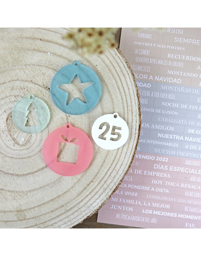 Pendentes festivos azuis, rosa e branco com formas recortadas sobre superfície branca texturada, com folha rosa com texto em espanhol ao lado.