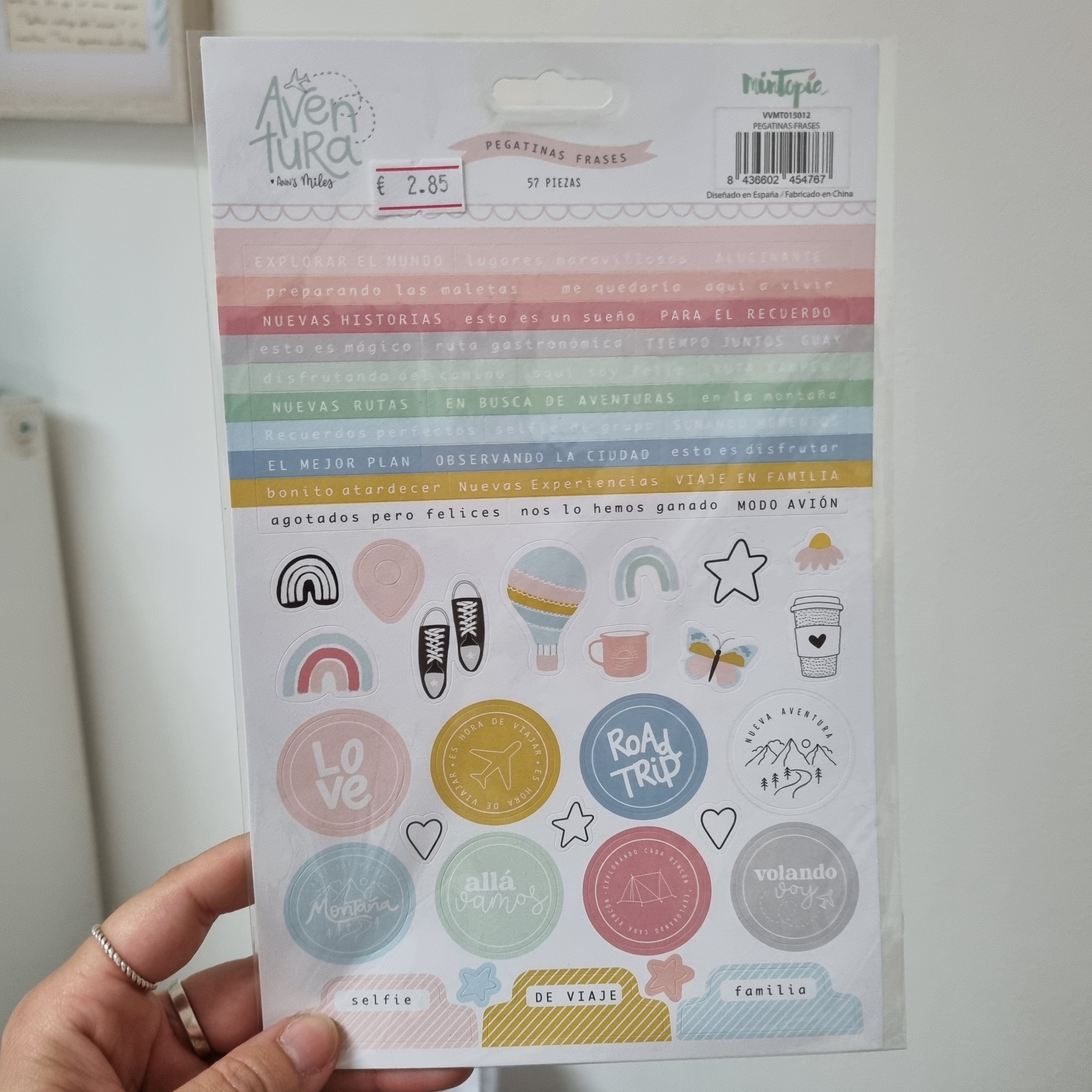 Pacote de autocolantes coloridos com frases e desenhos, segurado por uma mão