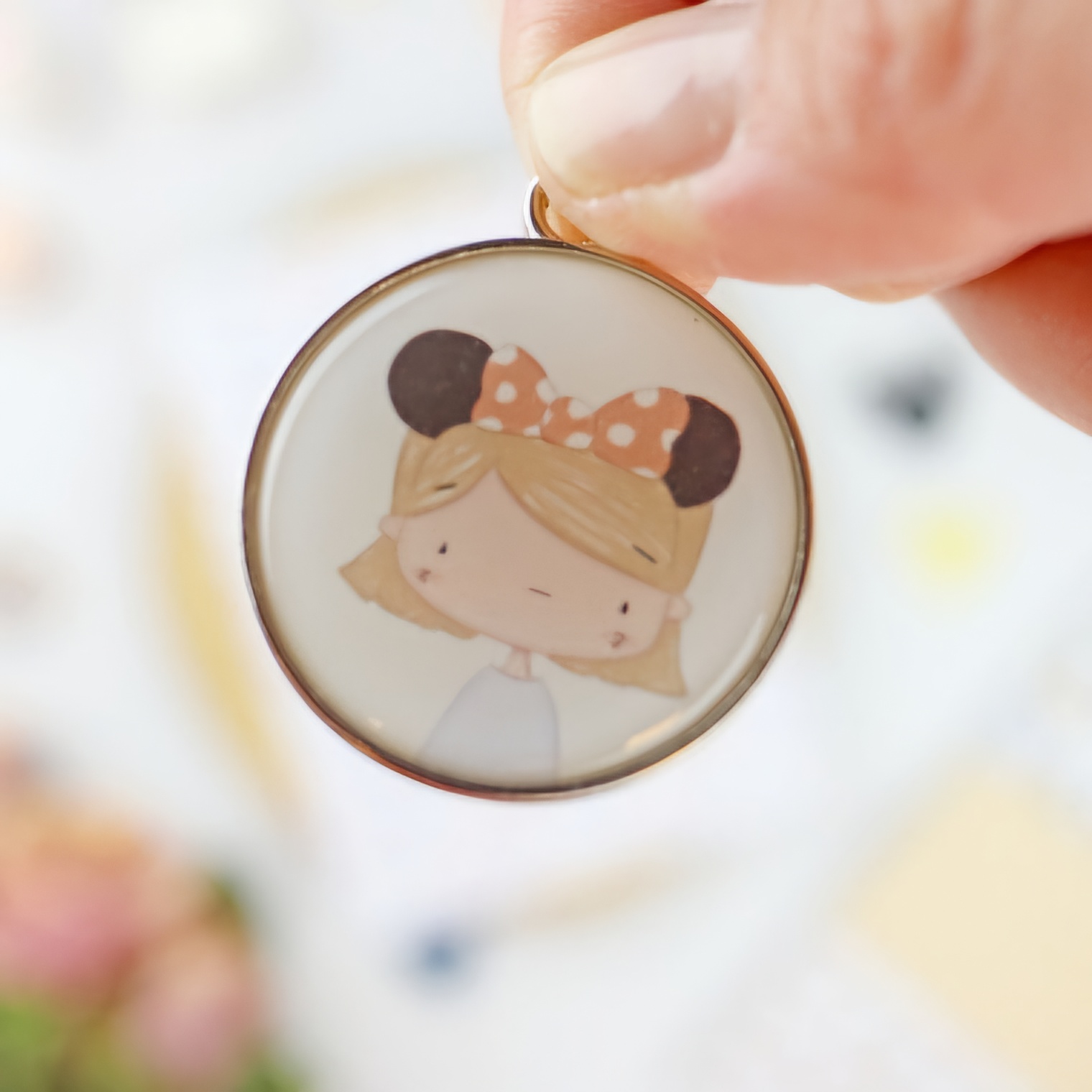 Medalha redonda com desenho de rapariga loira com laço e orelhas de rato