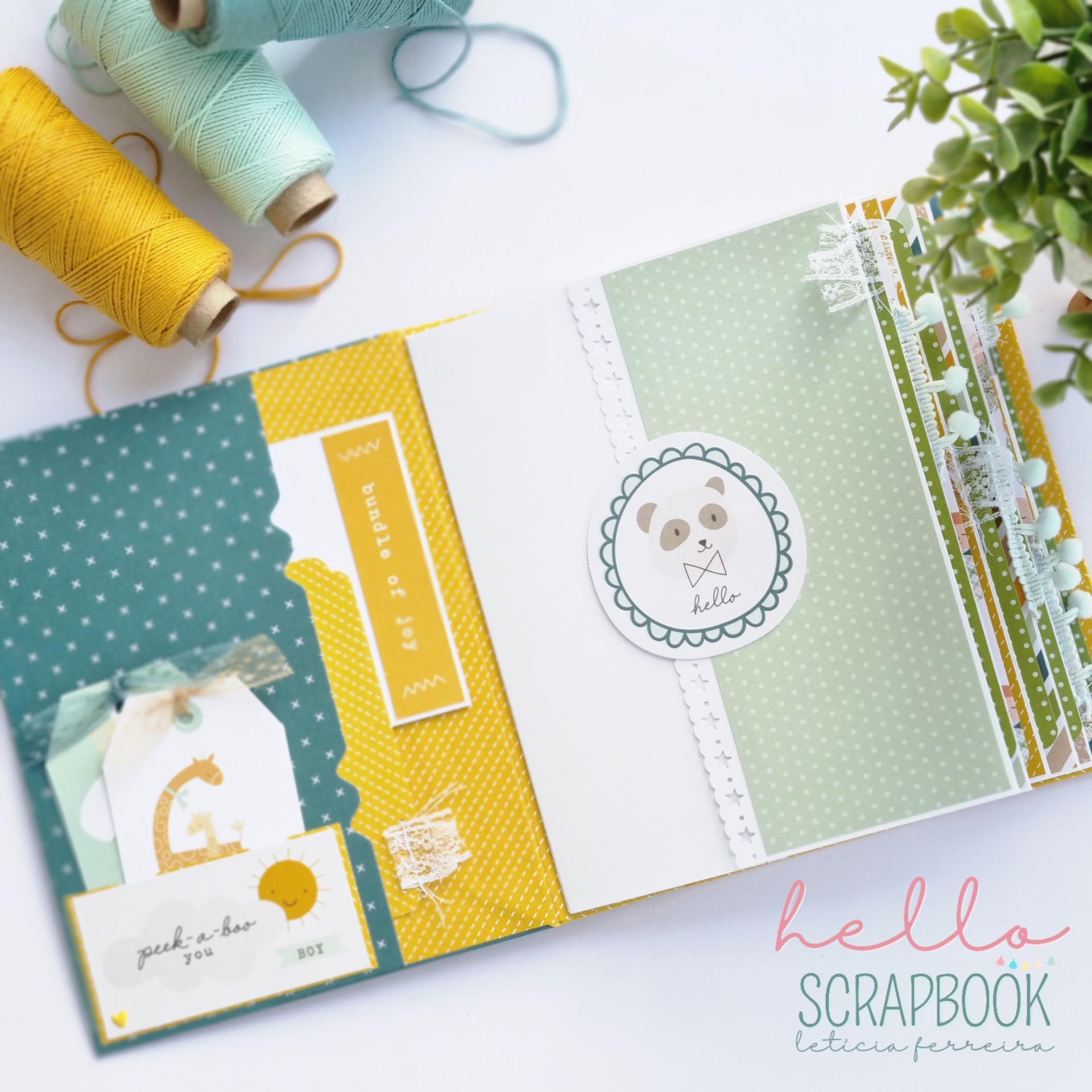 Álbum de scrapbook decorado aberto com linhas de costura e planta perto.