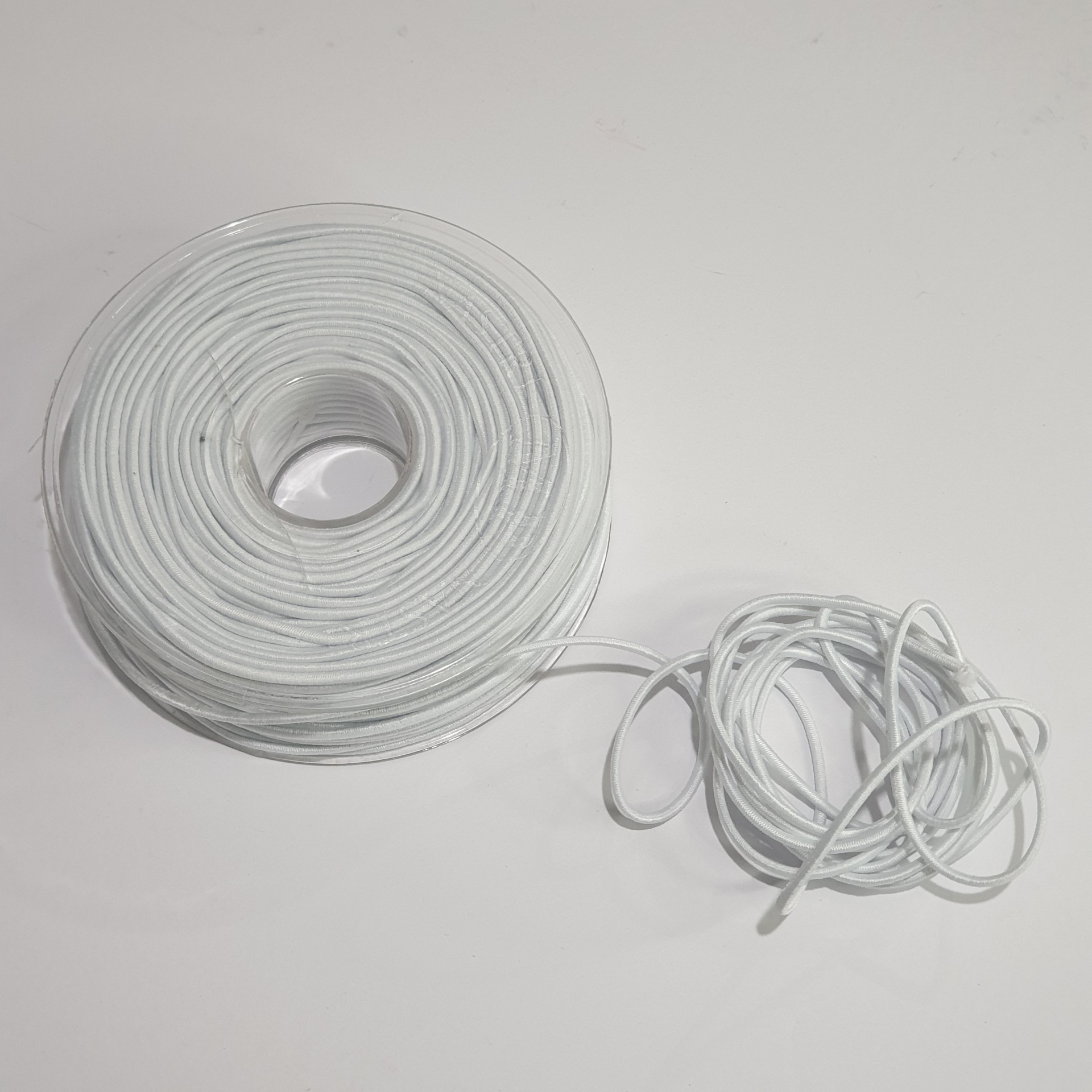 Rolo de fio branco fino enrolado com fio solto ao lado