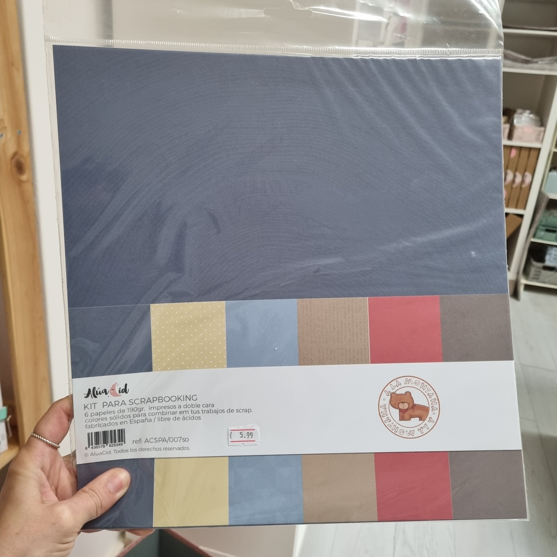 Kit para scrapbooking com papéis coloridos em embalagem transparente e branca com logótipo de urso