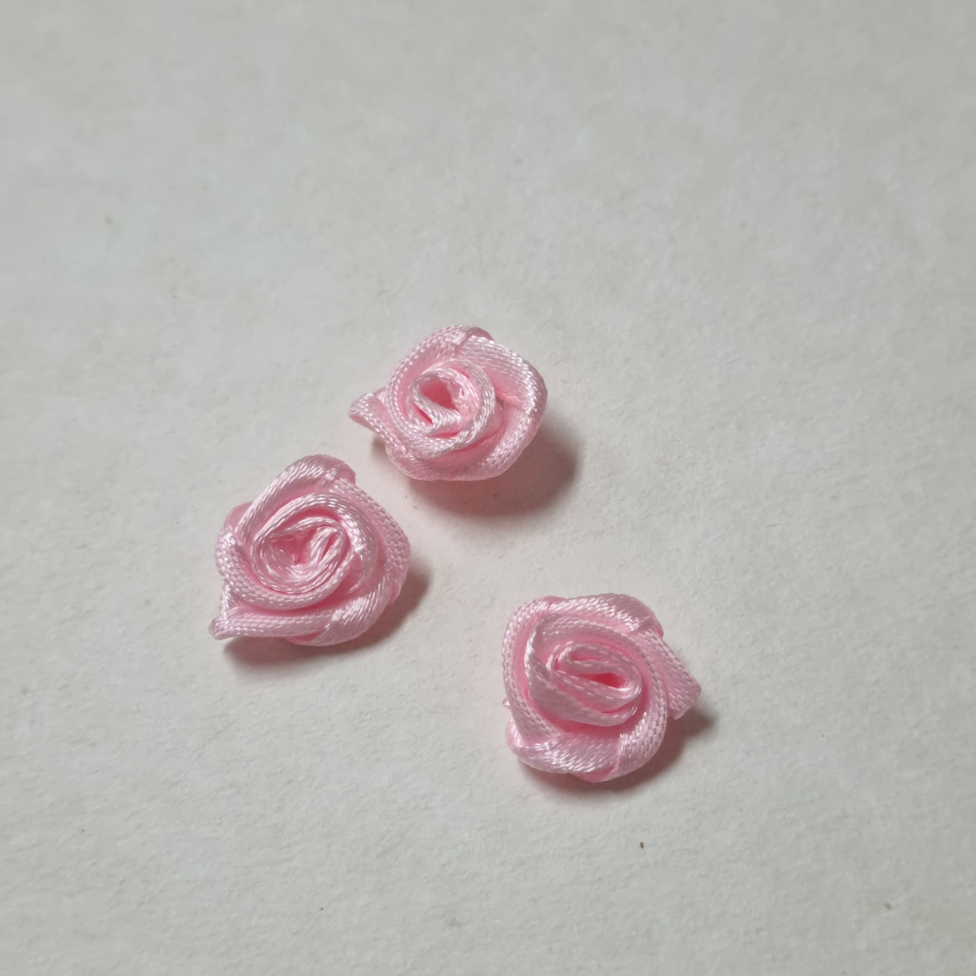 Rosas decorativas cor-de-rosa de fita de cetim sobre fundo branco