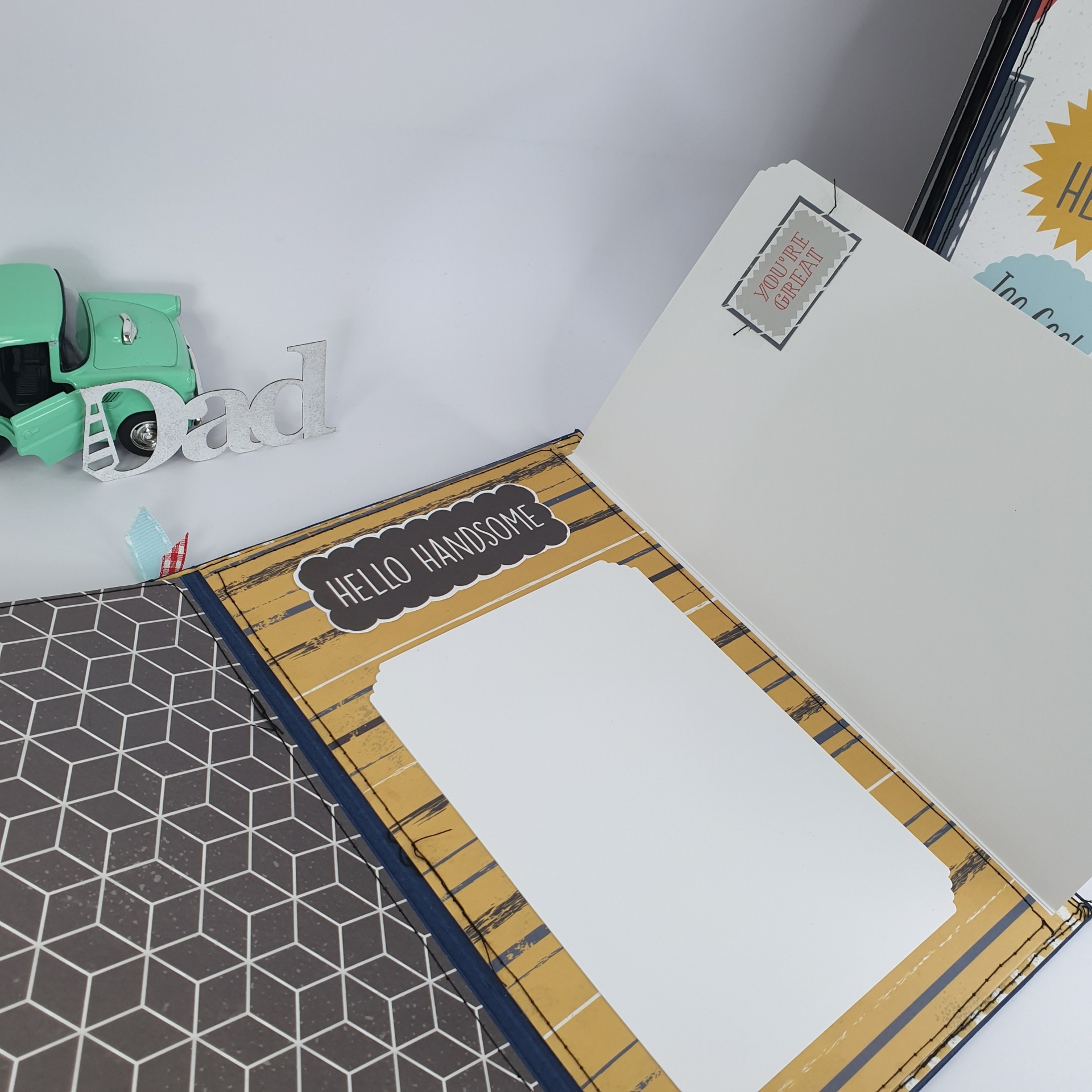 Álbum de scrapbook aberto com espaço para fotografia e textos decorativos em padrão amarelo e cinza.