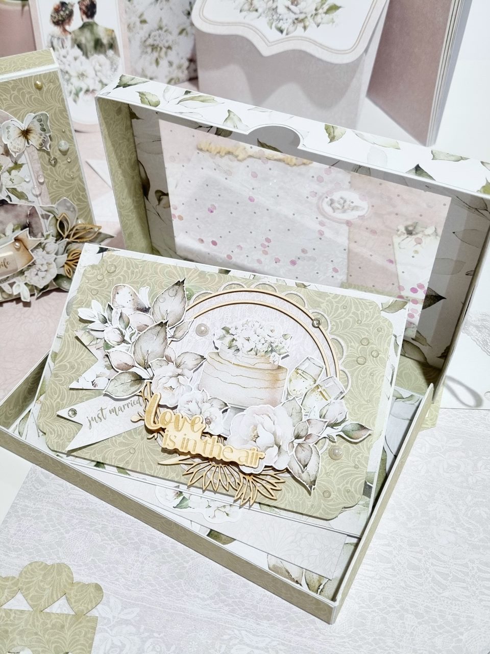 Cartão decorativo floral em tons bege e cinza com texto 'love is in the air'