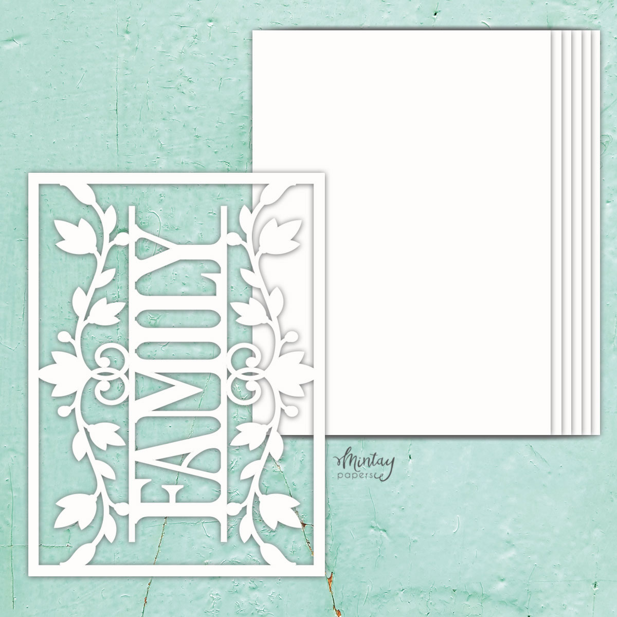 Recorte branco decorativo com a palavra FAMILY e folhas, junto a folhas brancas empilhadas