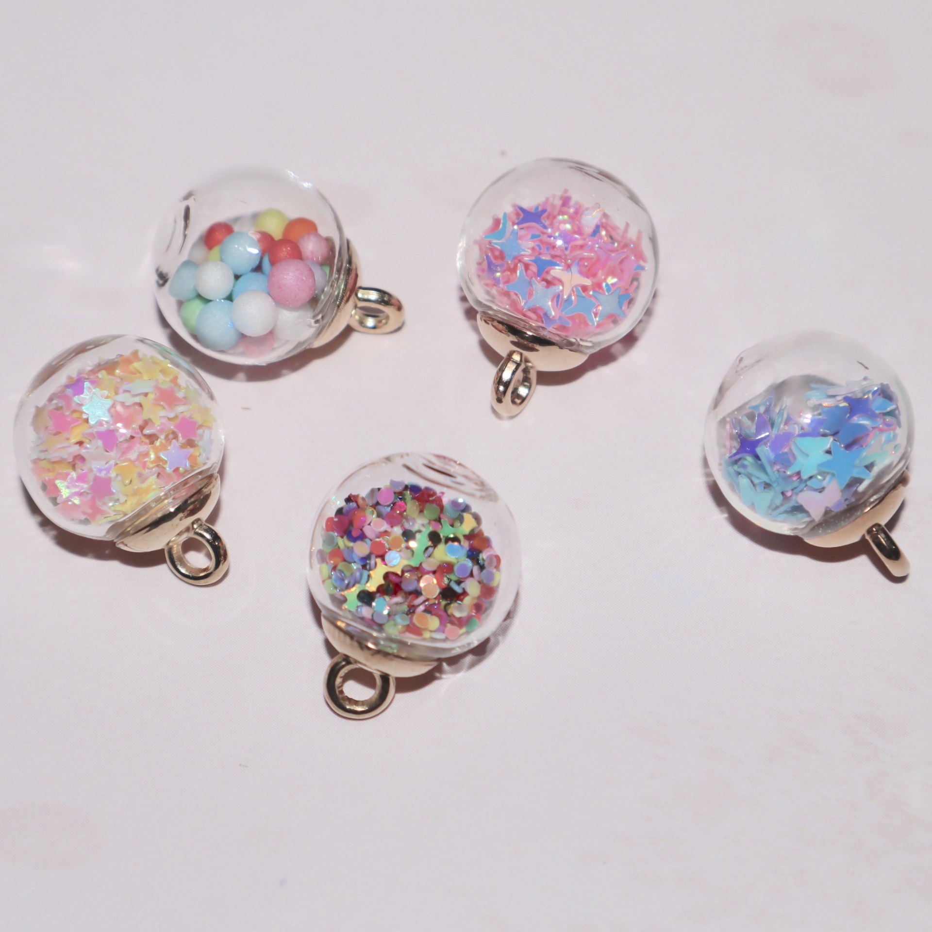 Cinco pendentes esféricos transparentes coloridos com argolas douradas