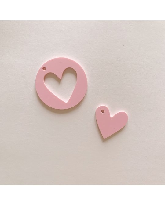 Dois pendentes rosa em forma de coração, um recortado e outro cheio, sobre fundo branco.