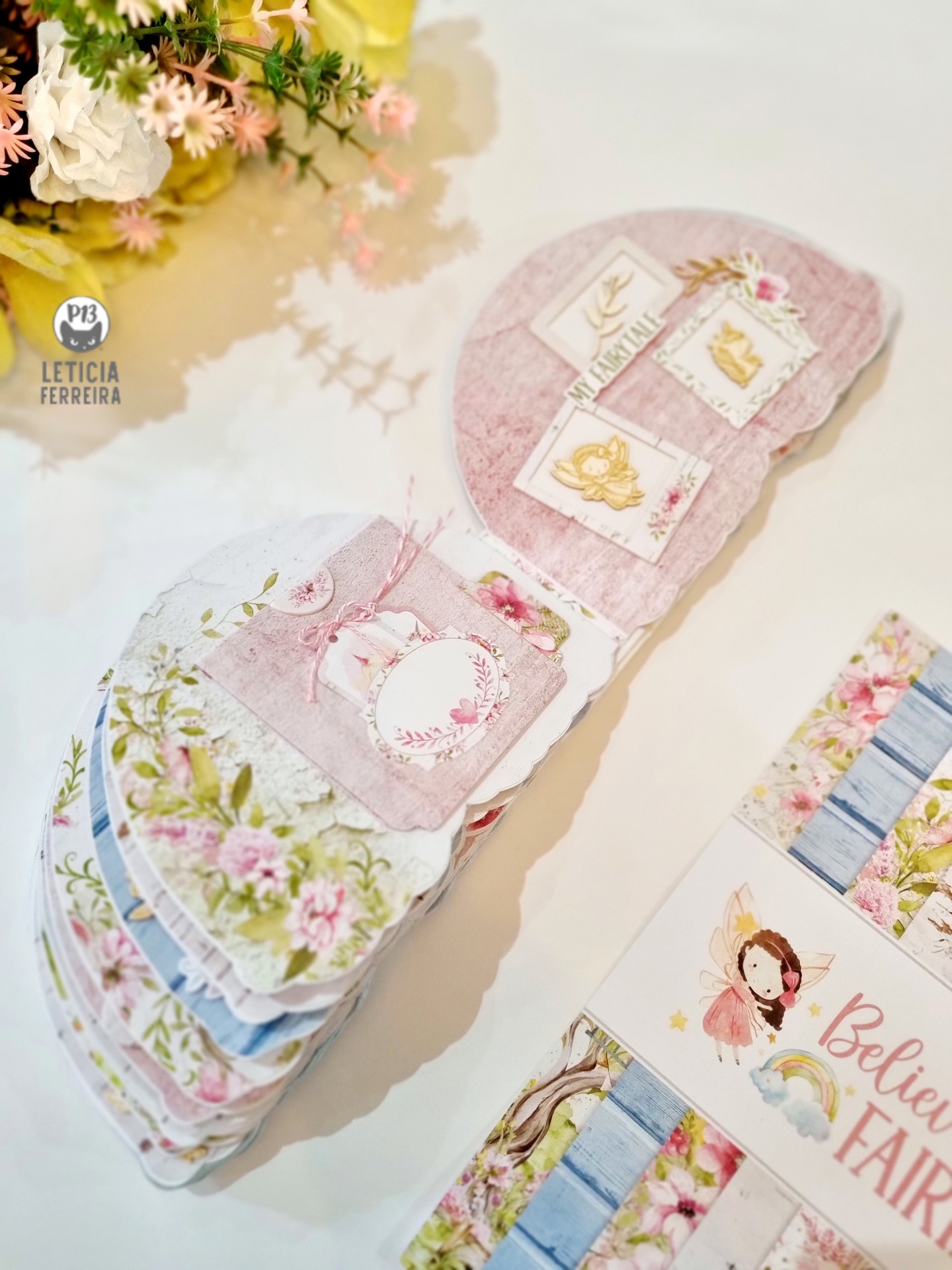 Álbum decorativo com páginas florais e ilustrações de fadas e animais