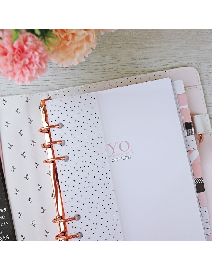Agenda rosa com argolas douradas e página com texto YO 2021/2022 próximo a flores cor-de-rosa
