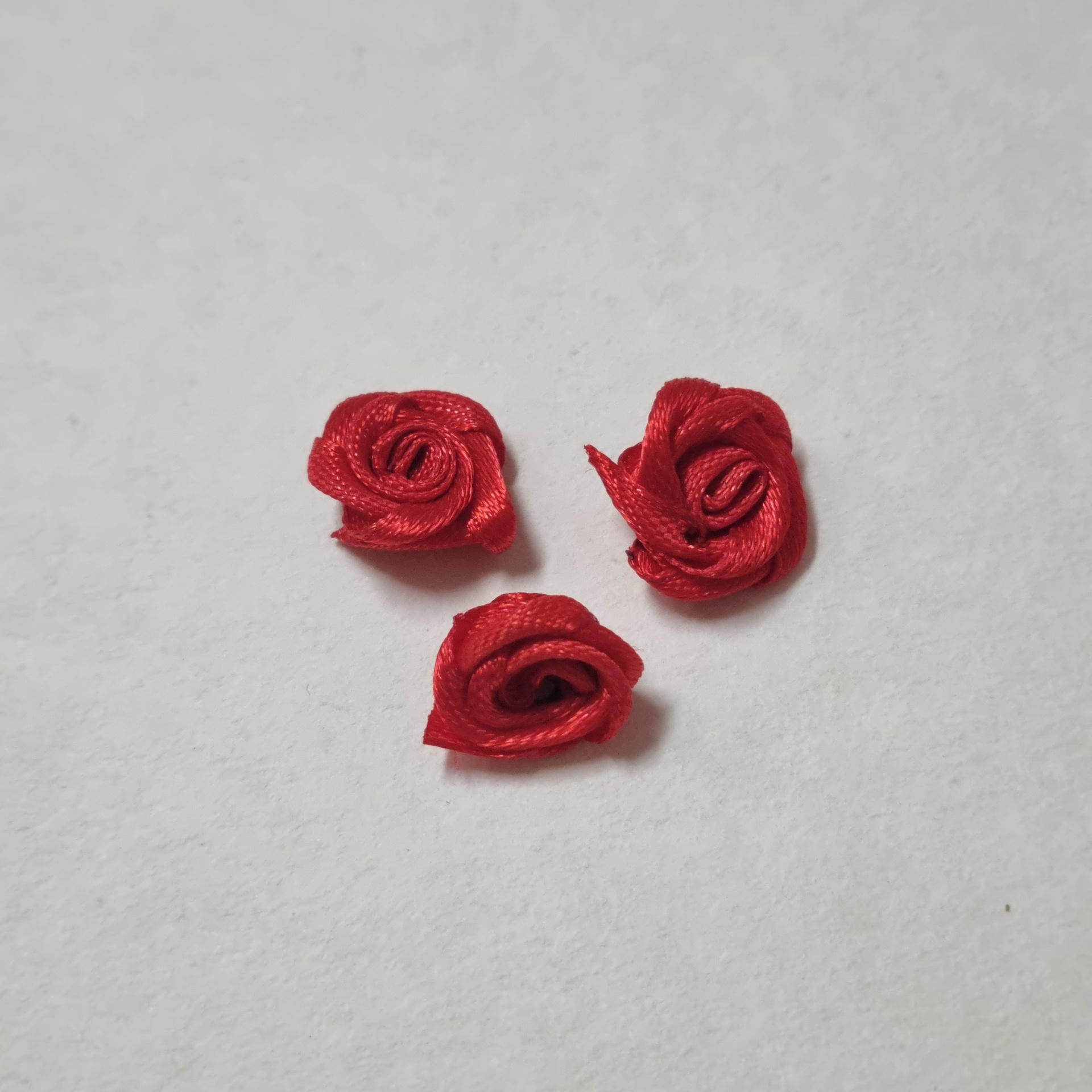 Flores vermelhas pequenas feitas de fita de cetim