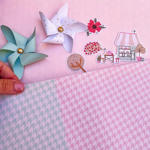 Papel de embrulho pied-de-poule rosa e azul com moinhos de vento em papel e autocolantes decorativos sobre fundo rosa
