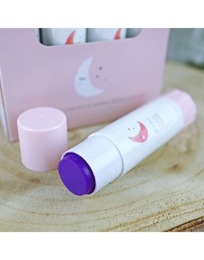 Bálsamo em stick com tampa rosa e corpo branco com desenho de lua, sobre madeira