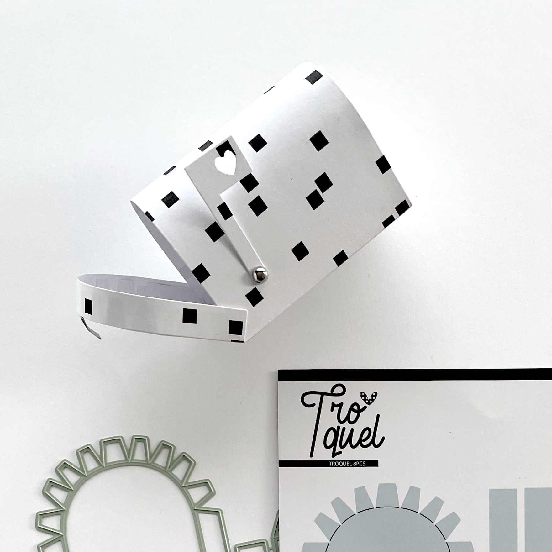 Cesta branca com padrão de quadrados pretos e coração recortado na alça, moldes de silicone e cartão Tro Quel