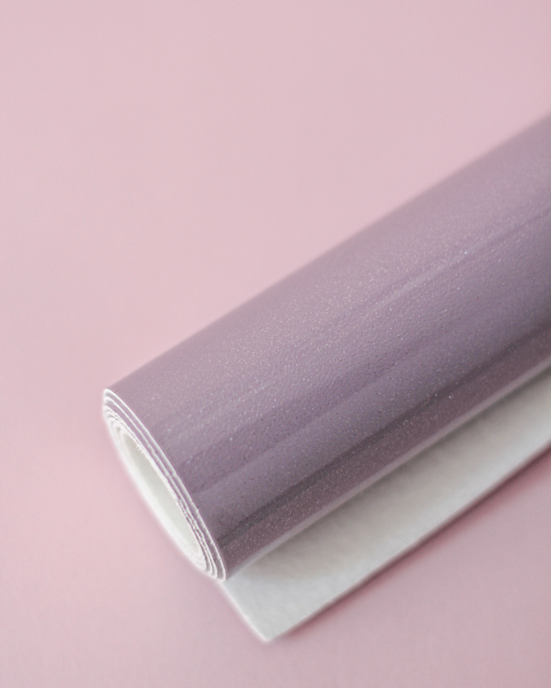 Rolo de vinil autocolante lilás brilhante sobre fundo rosa