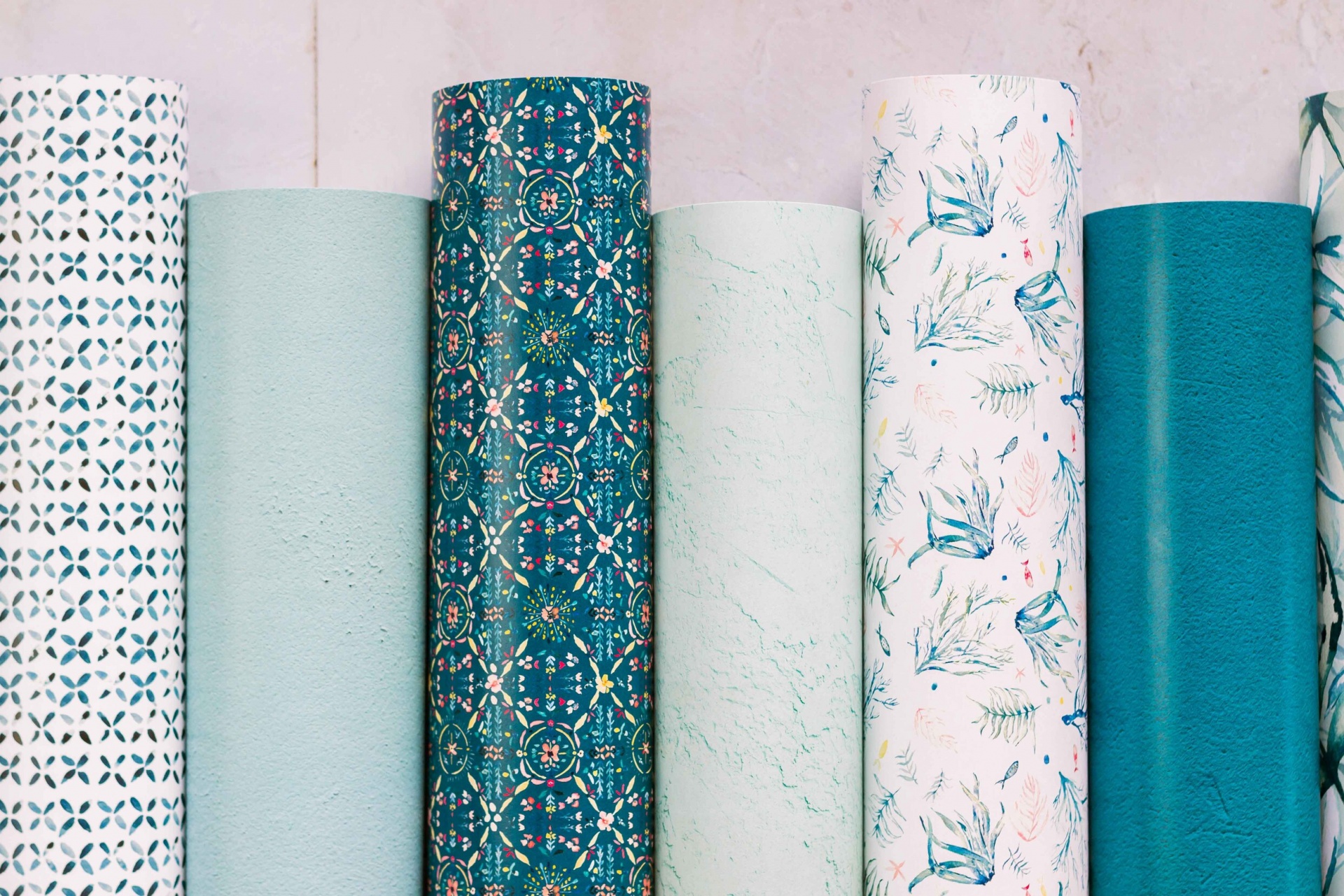 Sete rolos de tecido ou papel de embrulho com vários padrões e cores em suporte vertical