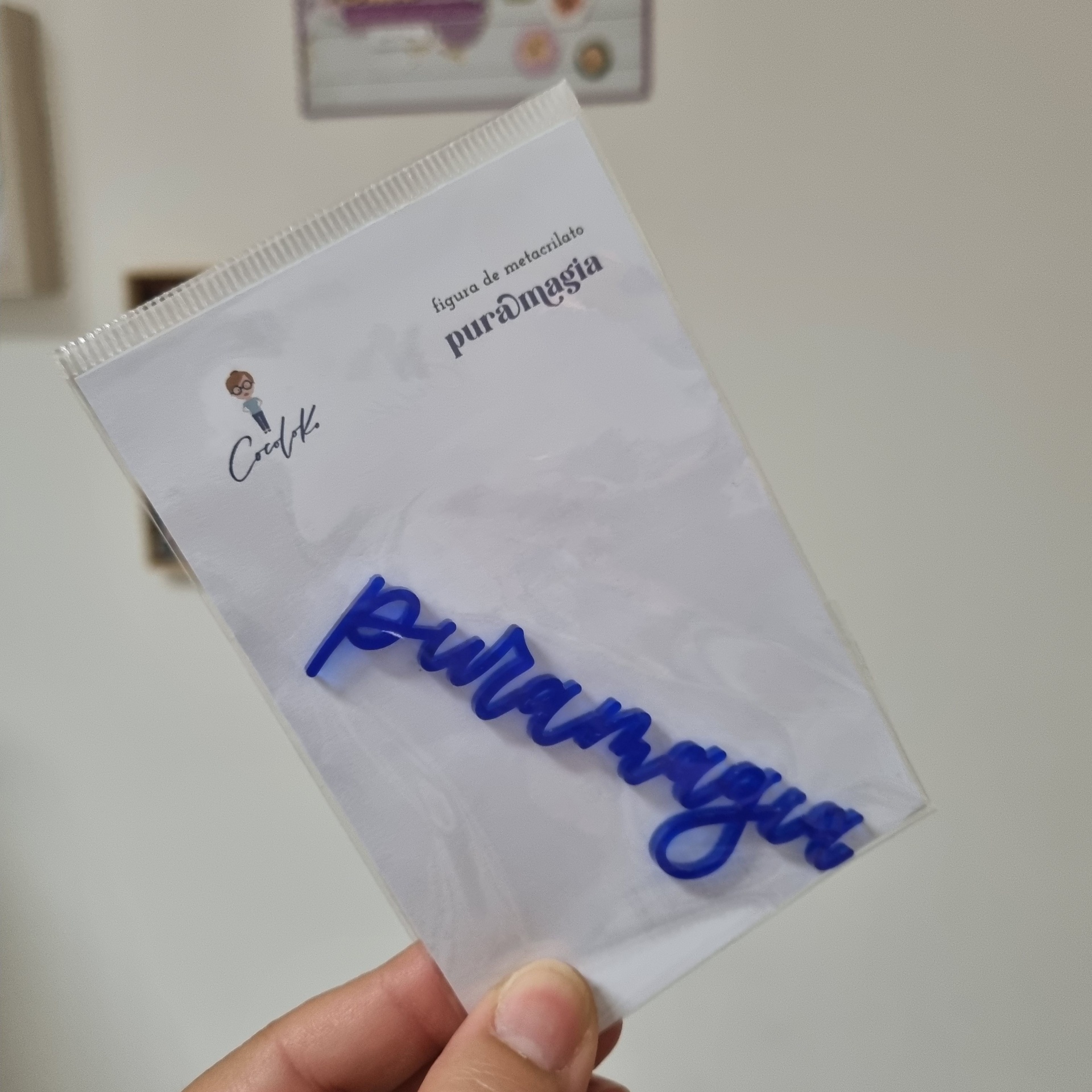 Embalagem com figura de metacrilato azul e texto pura magia