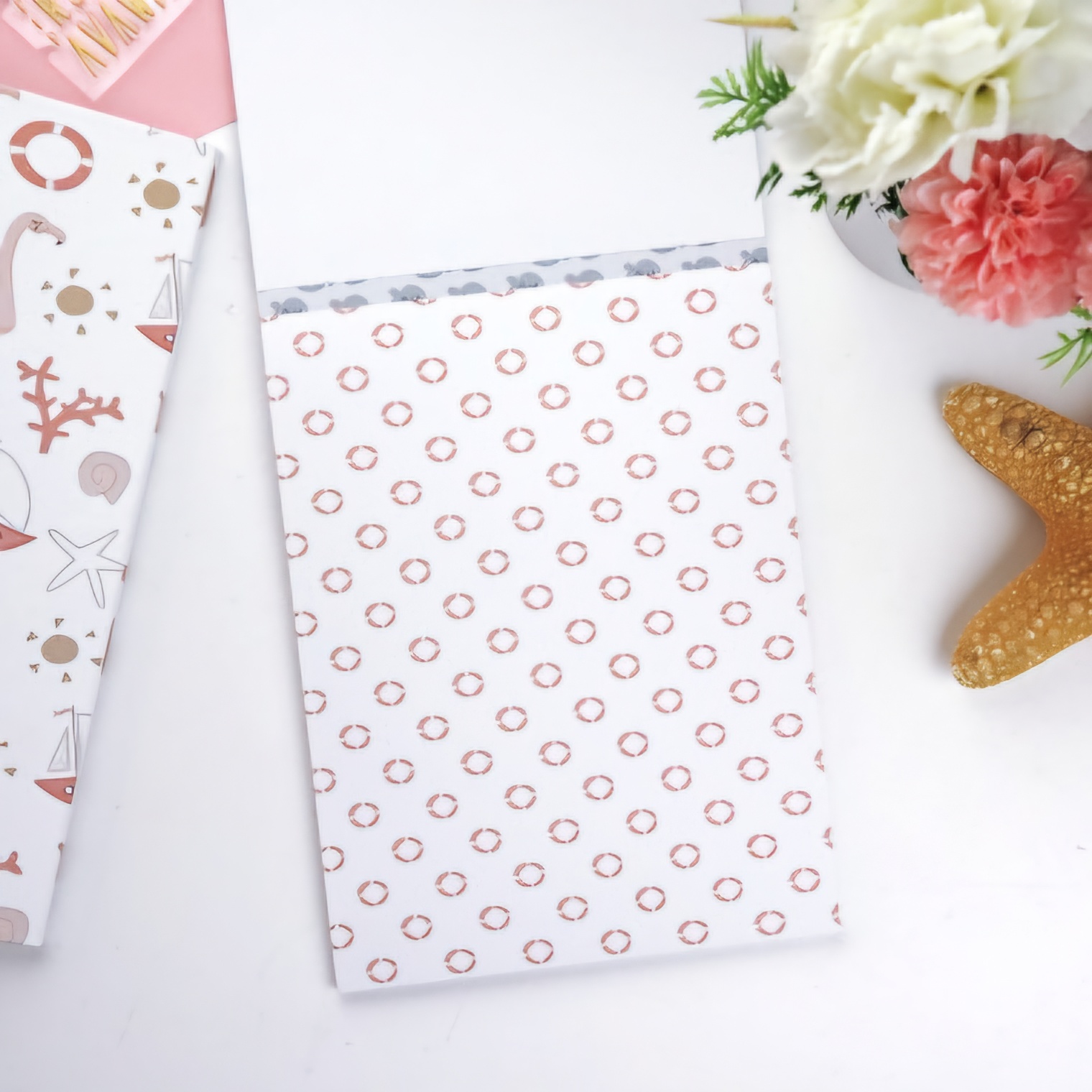 dois cadernos decorativos, flores artificiais e estrela-do-mar sobre fundo branco