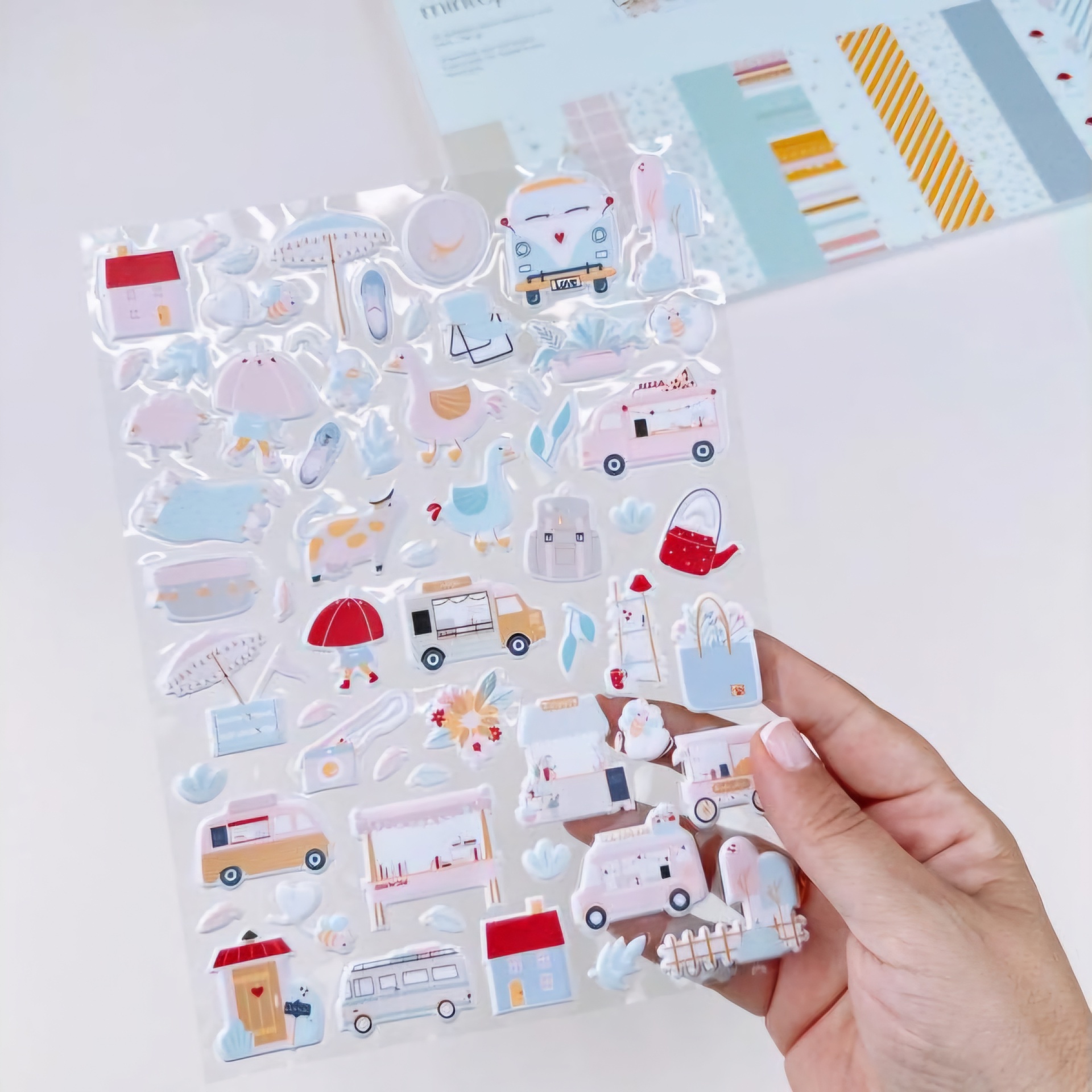 Mão a segurar autocolantes coloridos com imagens variadas e fundo desfocado.