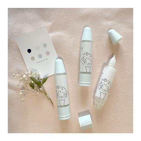 Três canetas brancas com ilustração de cordeiro, flores brancas e cartão com círculos coloridos sobre fundo rosa claro