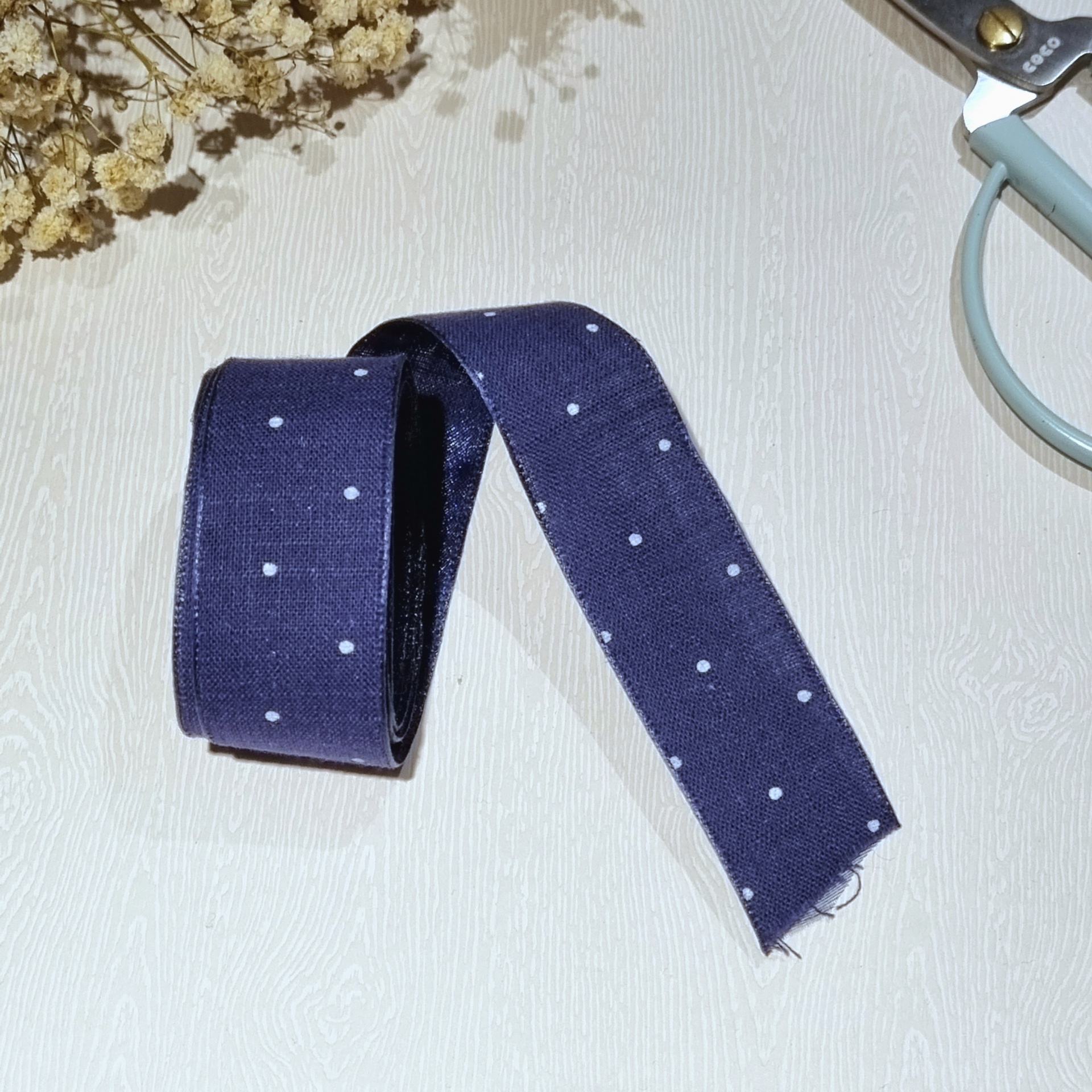 Fita de tecido azul com pontos brancos e tesoura