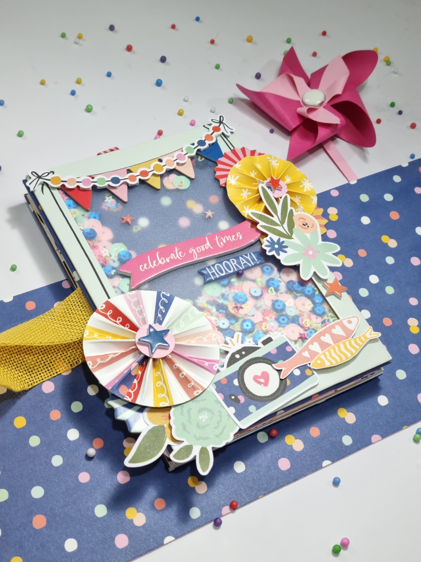 Caixa decorativa colorida com confetes e elementos festivos sobre tecido azul com bolinhas