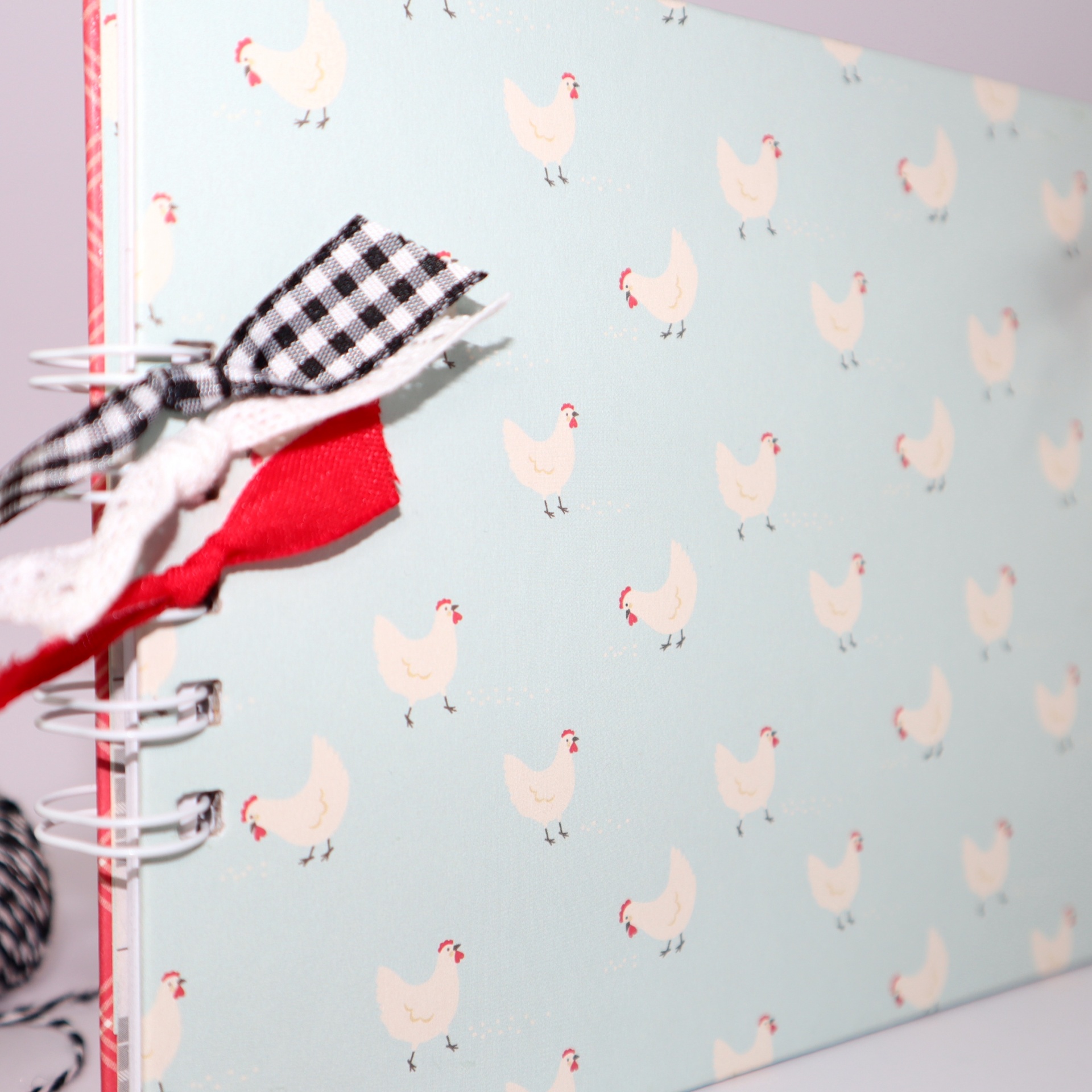 Caderno azul com padrão de galinhas e fitas no espiral
