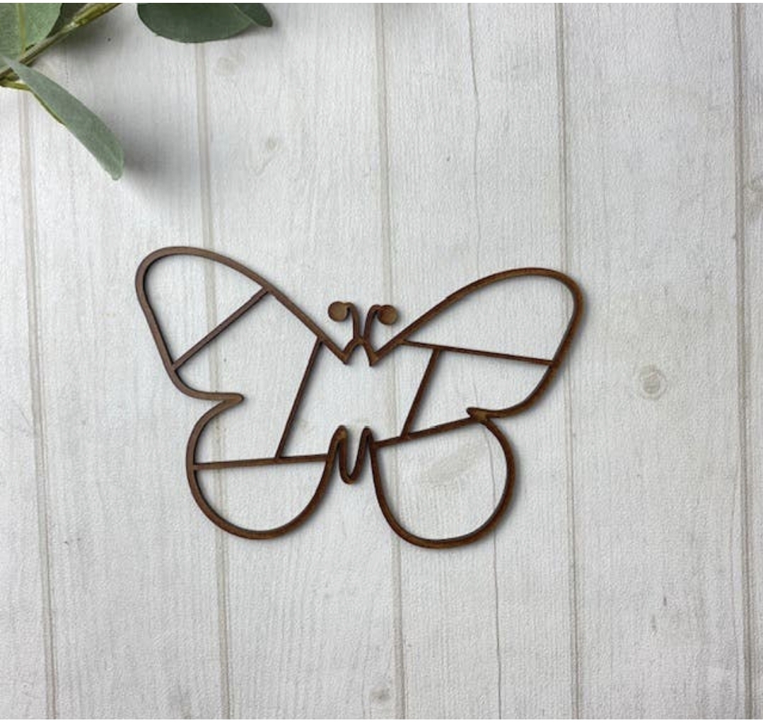 Objeto decorativo borboleta de arame castanho sobre madeira clara