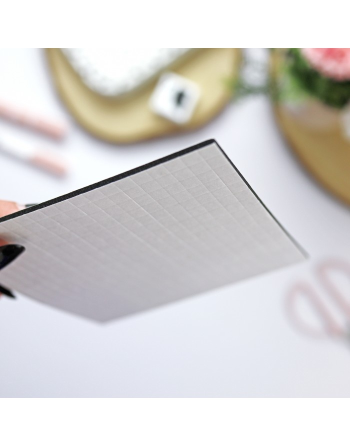 Placa fina branca com textura quadriculada segurada por uma mão.