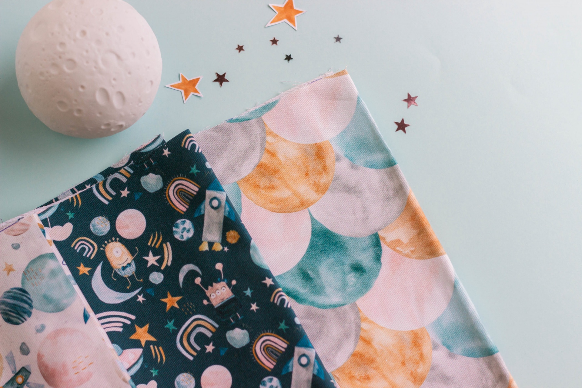 Tecidos estampados coloridos com padrão de unicórnios e escamas sobre fundo azul claro