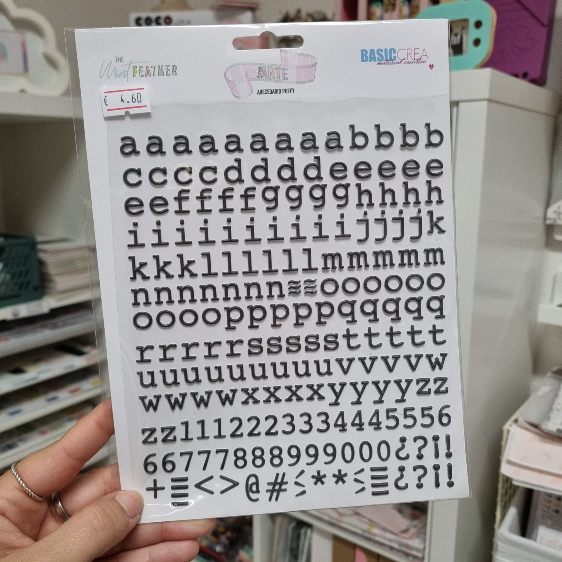Autocolantes de letras, números e símbolos em preto numa embalagem de cartão branco com etiquetas e textos visíveis.