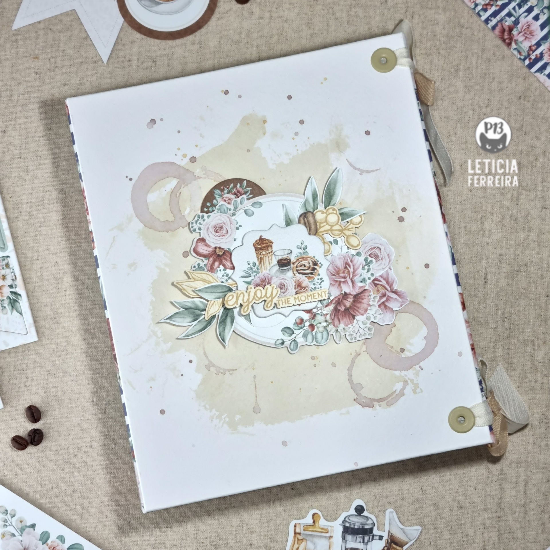 Álbum ou caderno com capa branca, flores e motivos de café em tons pastel sobre fundo bege.