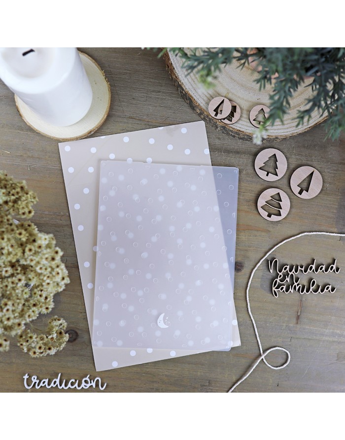 Conjunto de folhas decorativas com bolinhas, discos de madeira natalícios, texto em madeira, vela e plantas numa mesa de madeira.