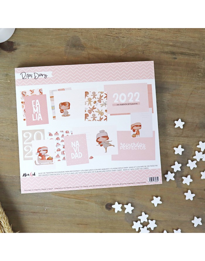 Calendário de mesa rosa com desenhos e textos para 2022 sobre mesa de madeira com estrelas brancas decorativas