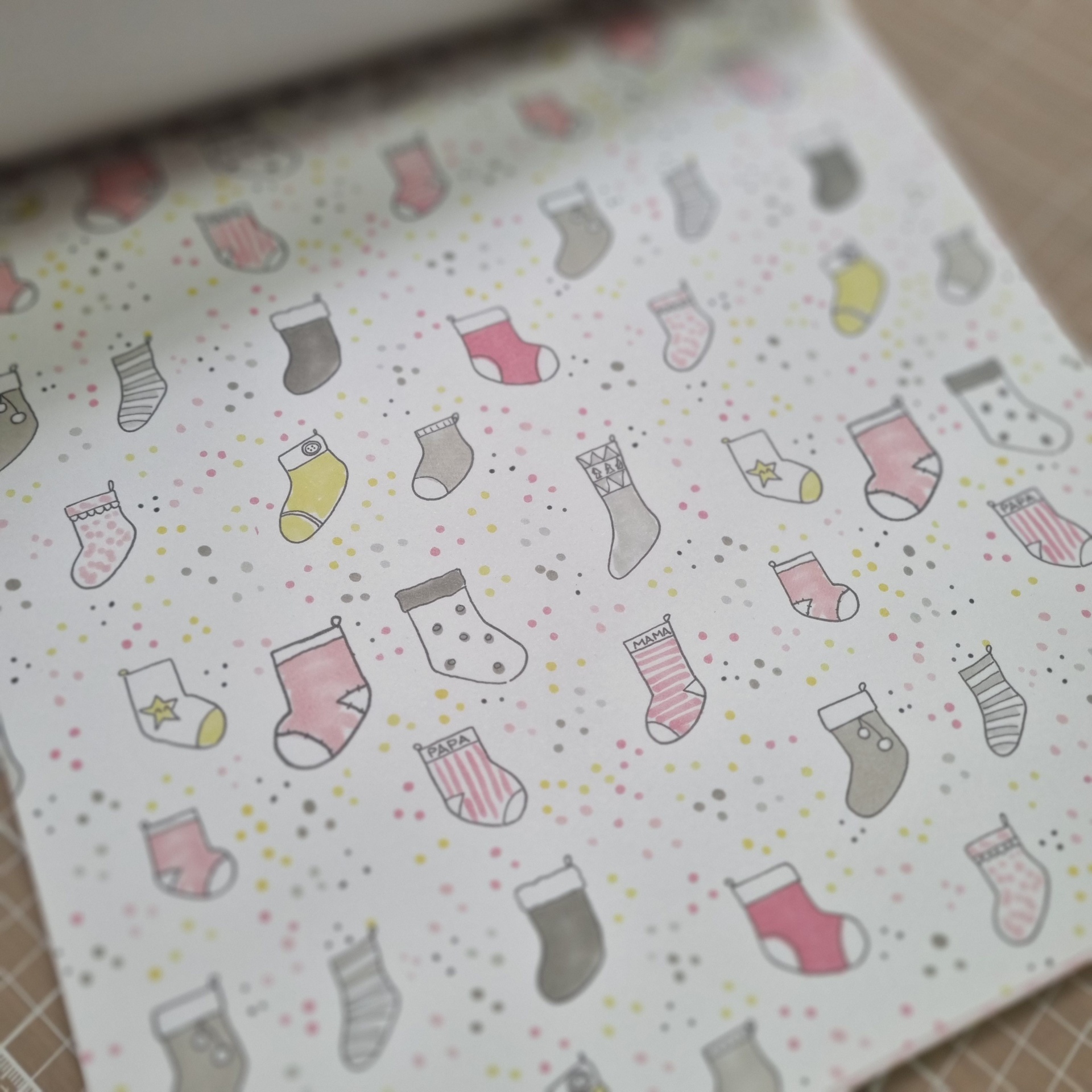Papel de embrulho com padrão de meias coloridas e pequenos pontos sobre fundo branco.