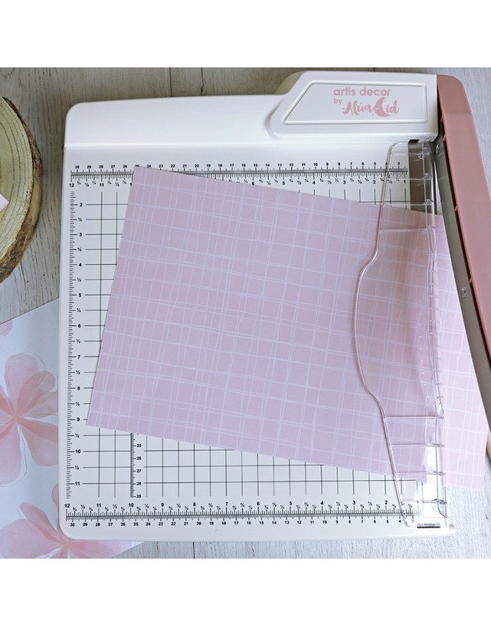 Guilhotina artesanal branca e rosa com base quadriculada e folha cor-de-rosa posicionada.