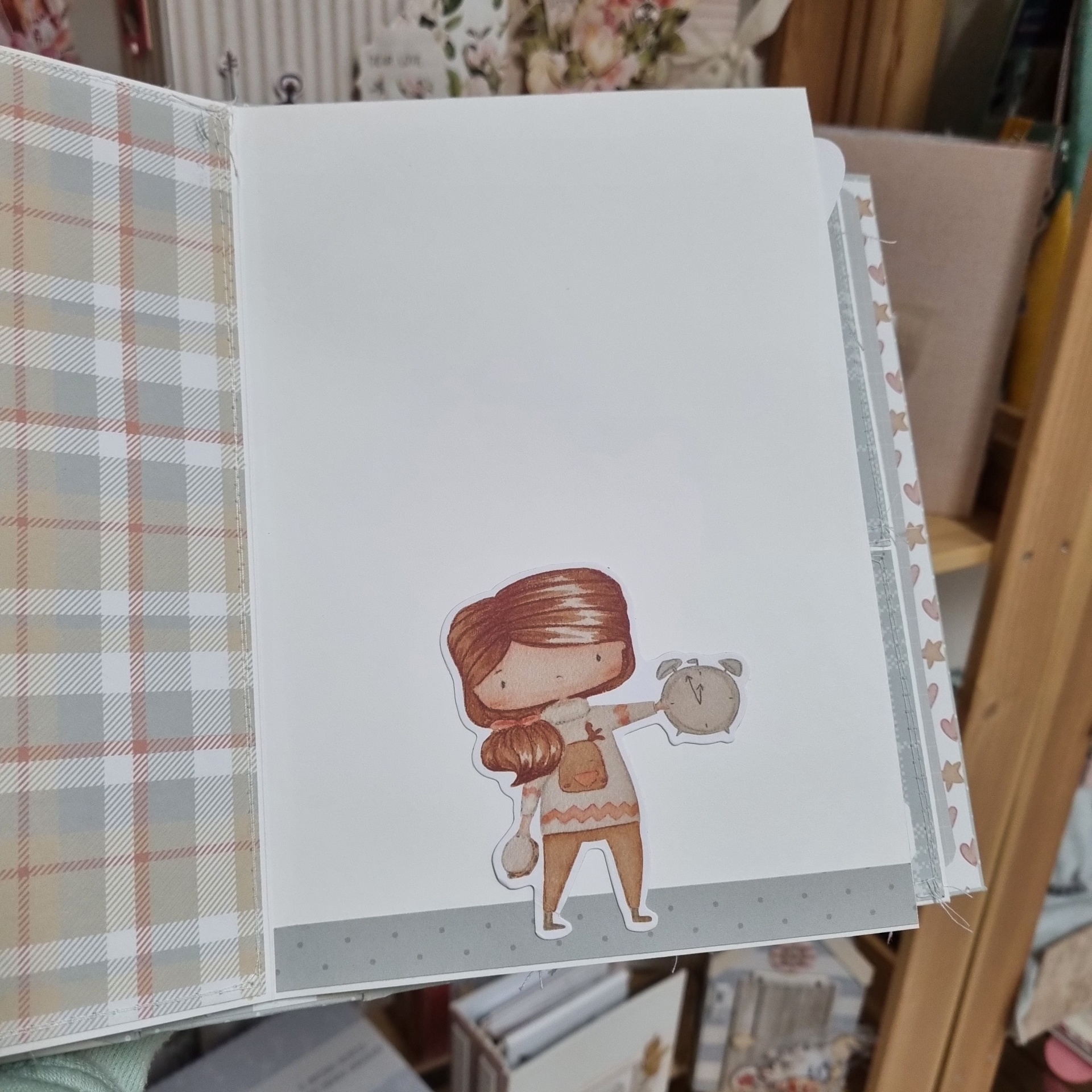 Página interna de álbum branco com ilustração de menina castanha segurando relógio