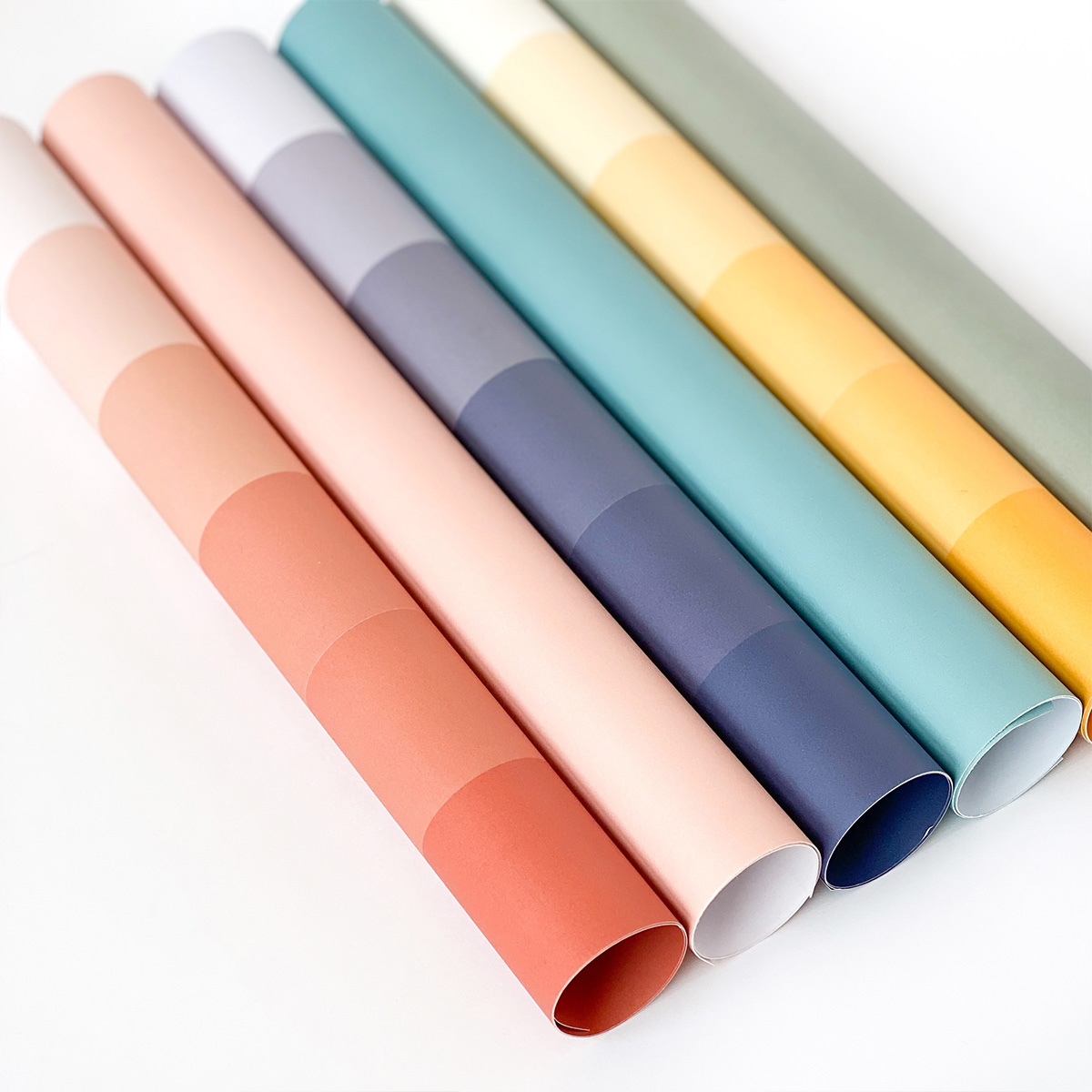 Cinco rolos de papel colorido em segmentos de cor variada colocados lado a lado