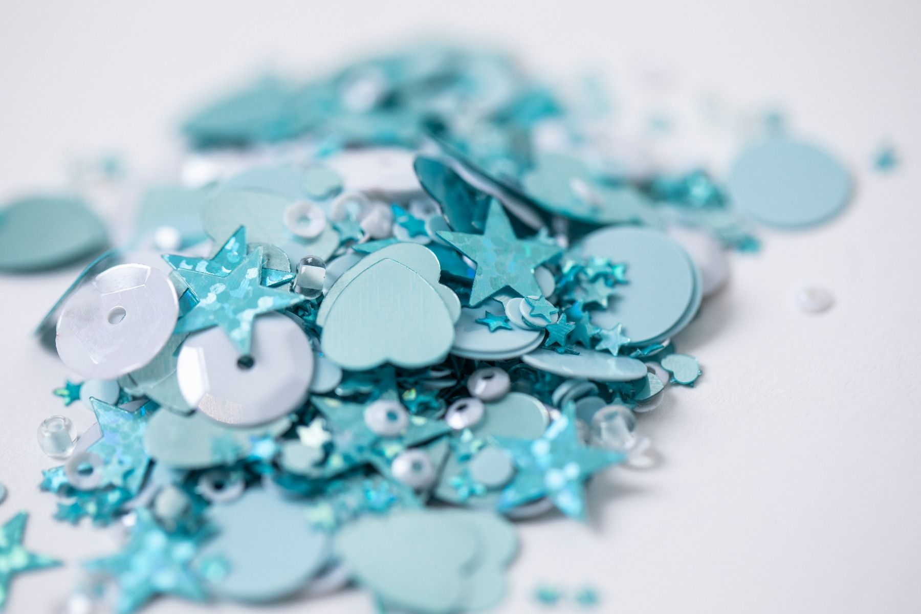 Lantejoulas azuis de várias formas sobre fundo branco