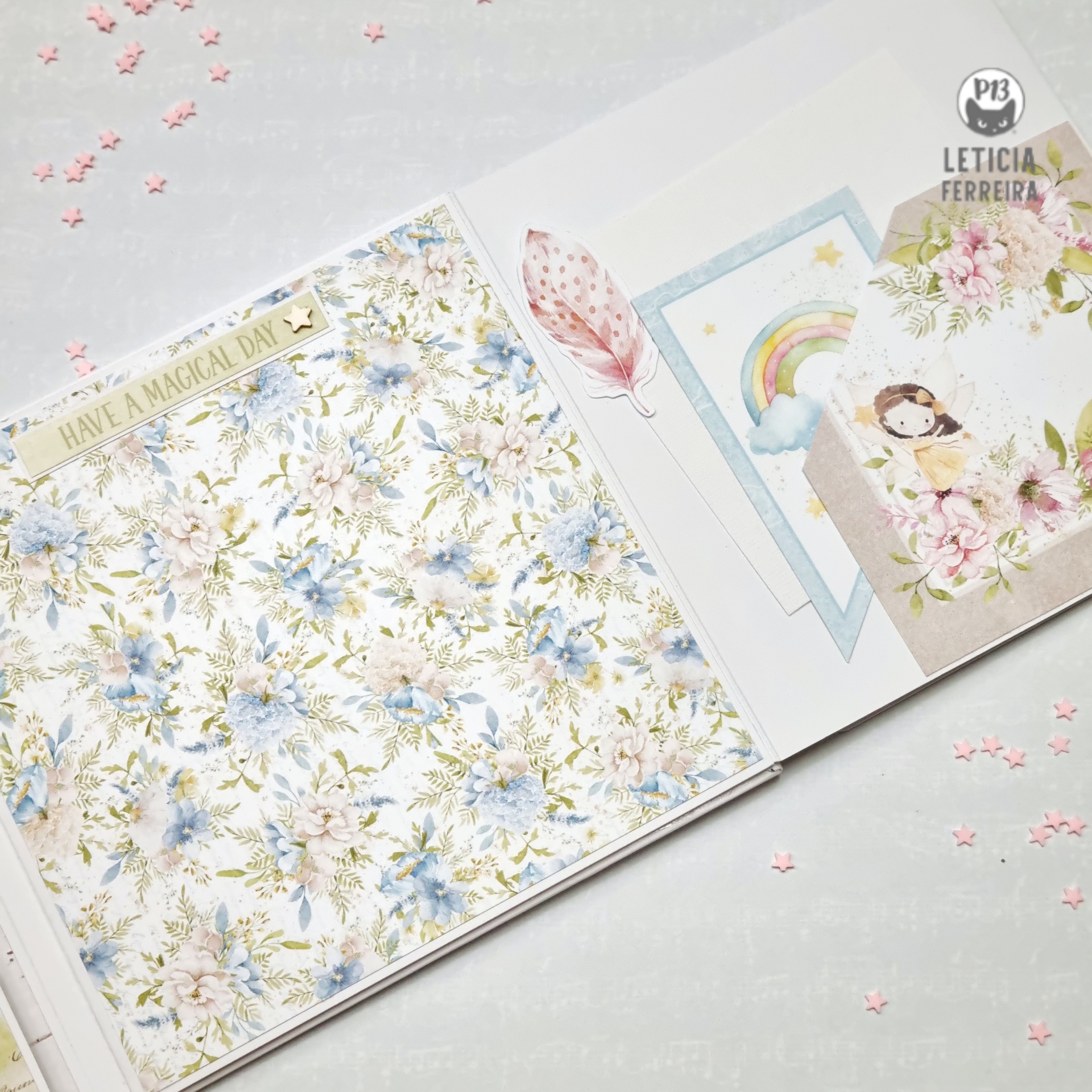 Livro aberto com páginas decoradas com padrão floral, pena, arco-íris, menina e flores cor-de-rosa.