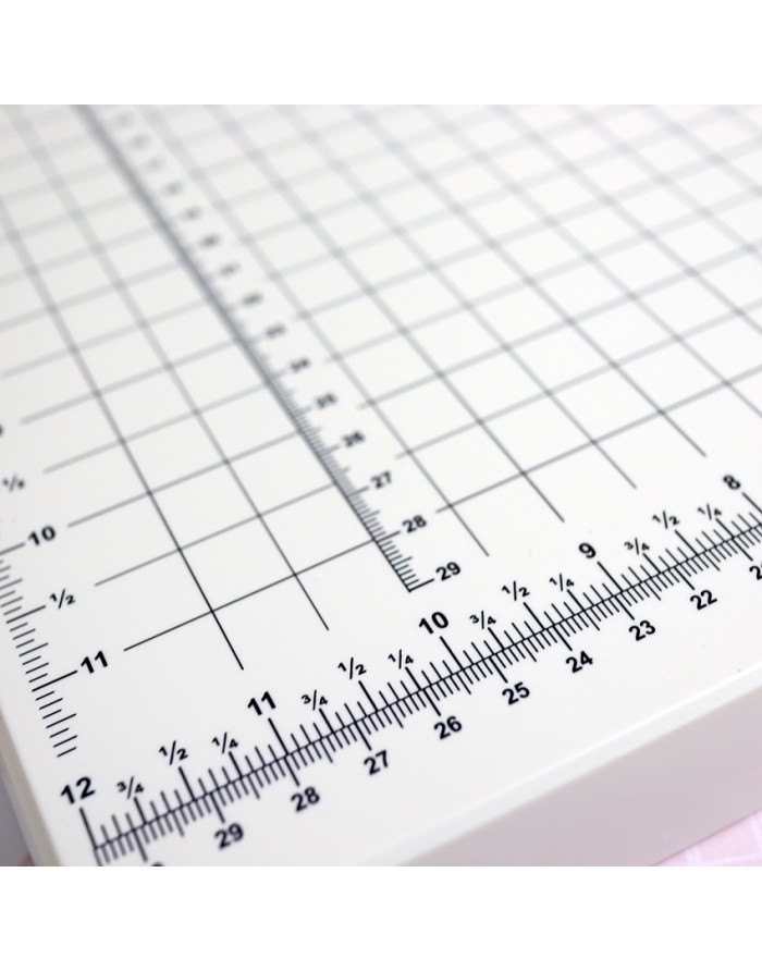 Mesa de corte branca com grelha e medidas em centímetros e polegadas
