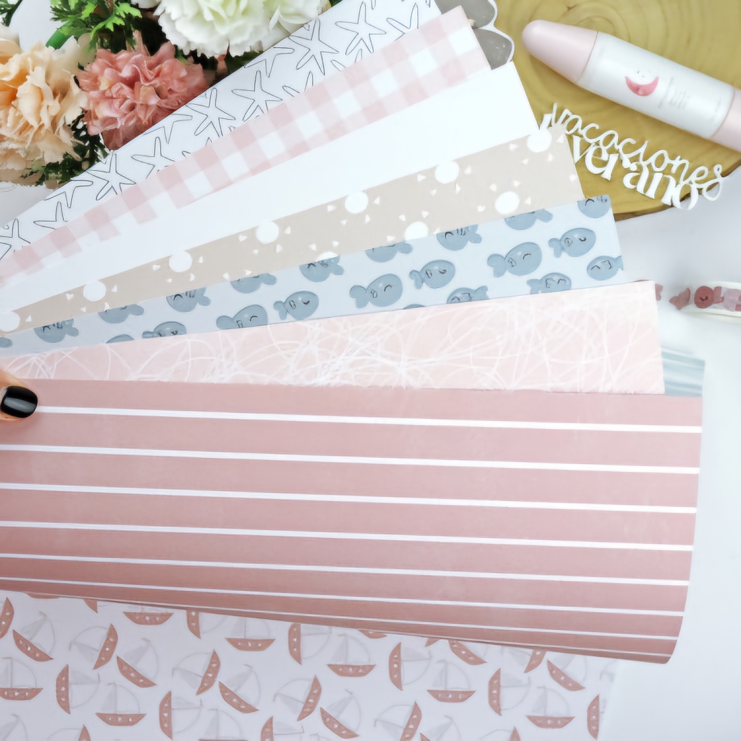 Folhas de papel decorativo com padrões pastel e vários desenhos sobre mesa de madeira