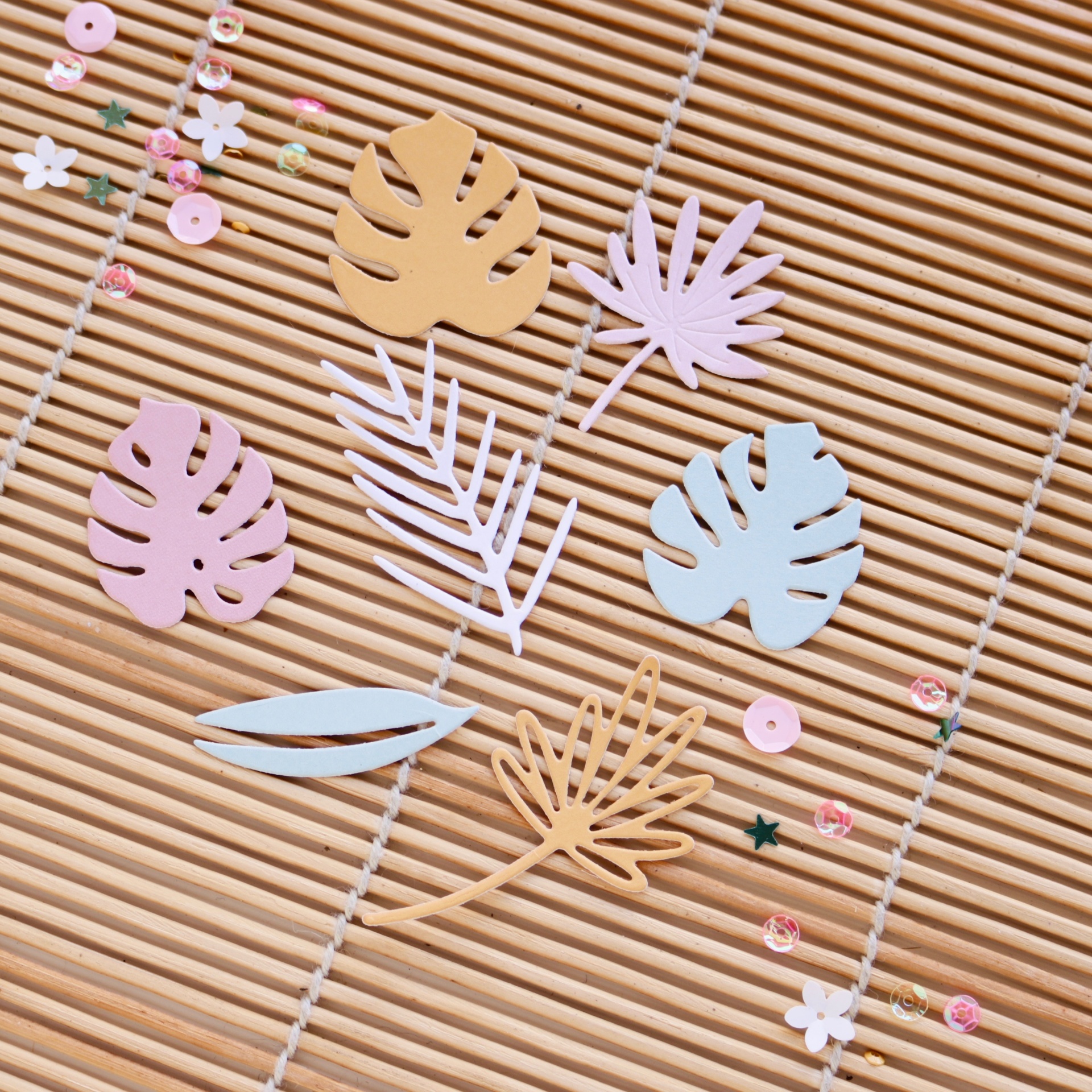 Folhas decorativas de papel coloridas sobre superfície de bambu com pequenas contas coloridas