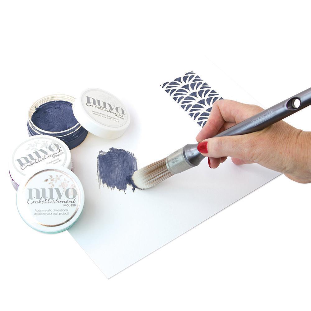 Potes de tinta Nuvo Embellishment e pincel a pintar num papel branco com padrão