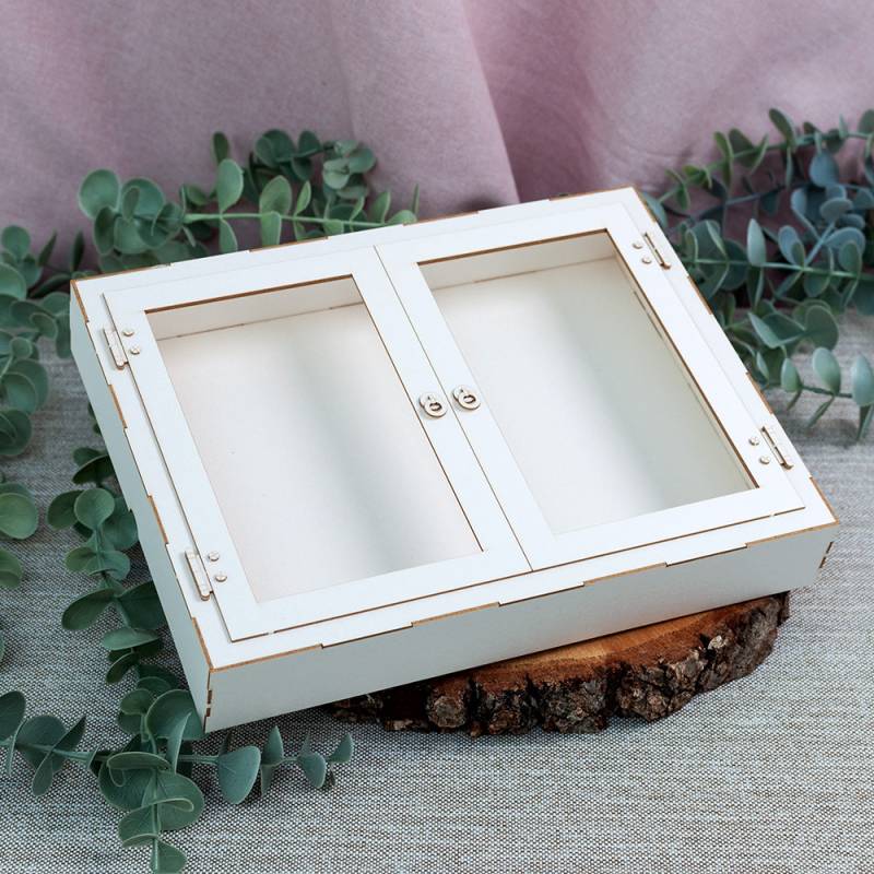 Caixa organizadora branca em madeira com tampa dupla sobre base de madeira rústica e folhas verdes