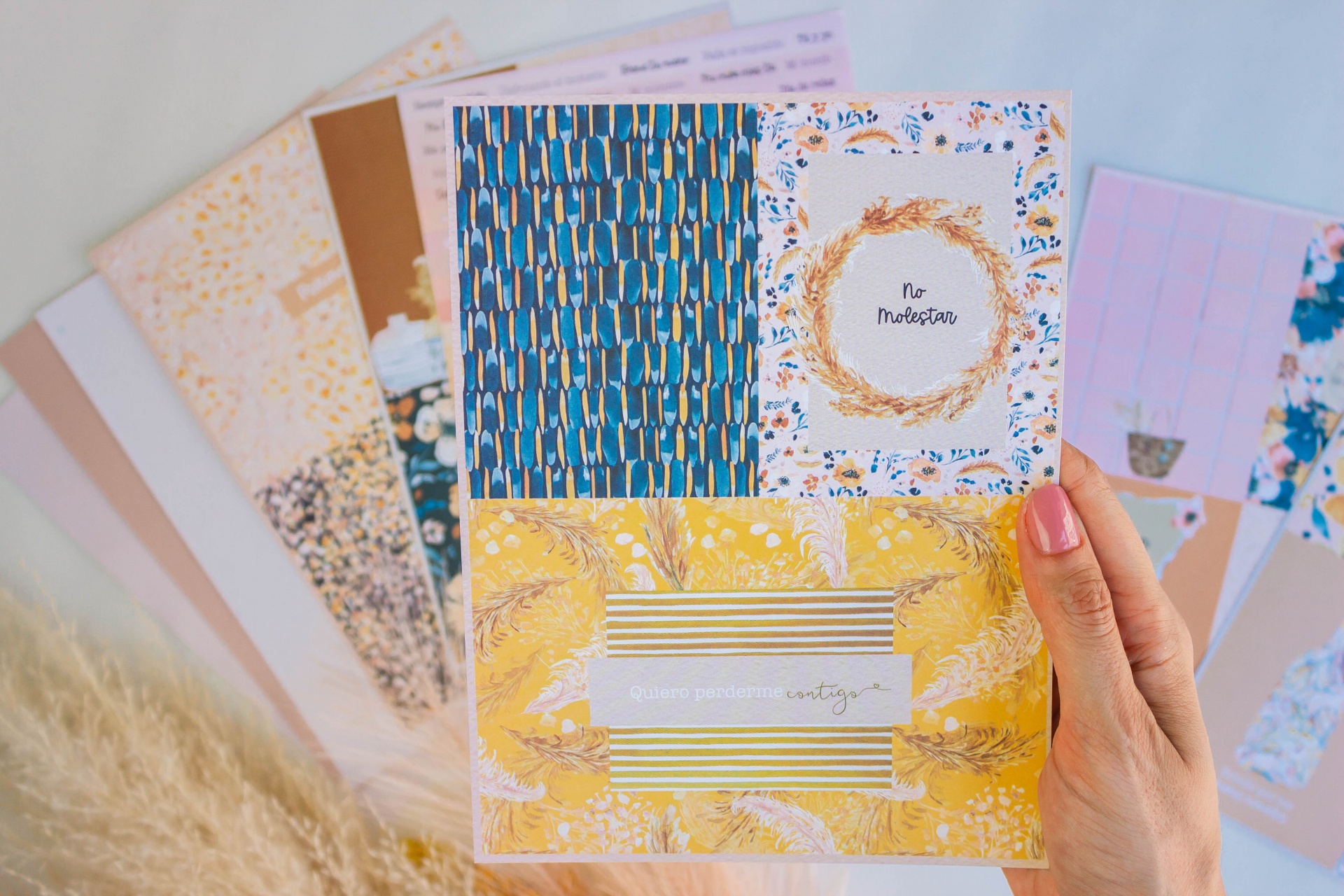 Bloco de notas decorado com padrões florais e geométricos em várias cores segurado por uma mão