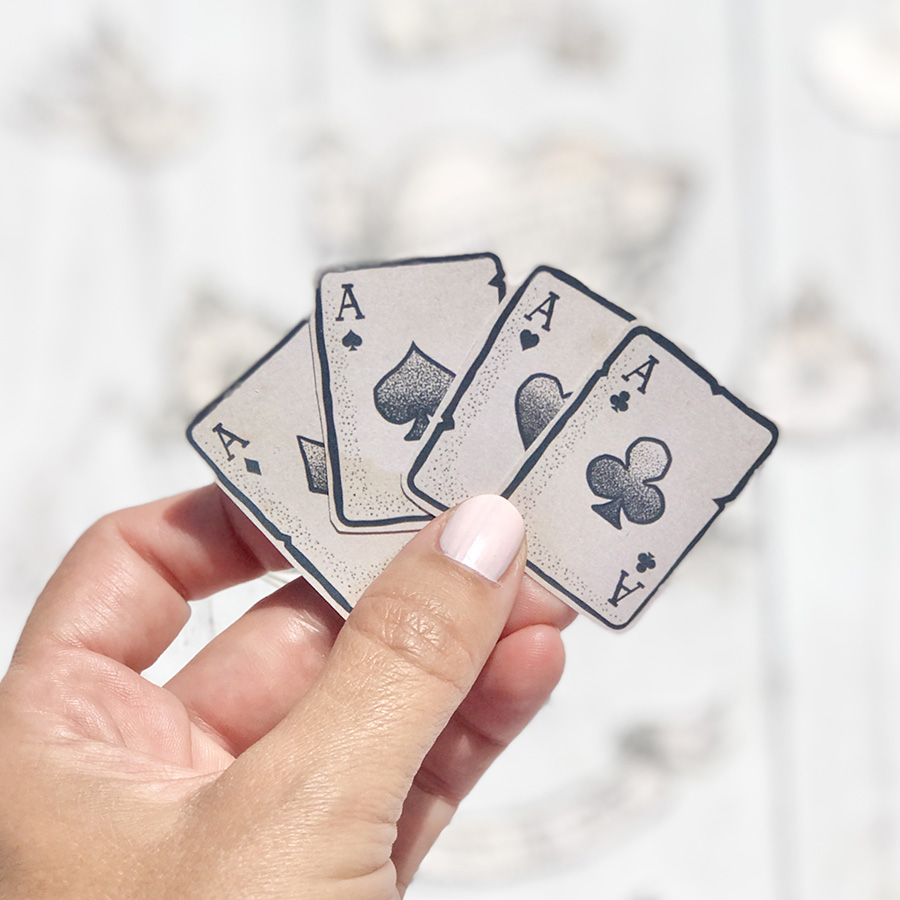 Mão segura quatro cartas de baralho envelhecidas com ases de diferentes naipes