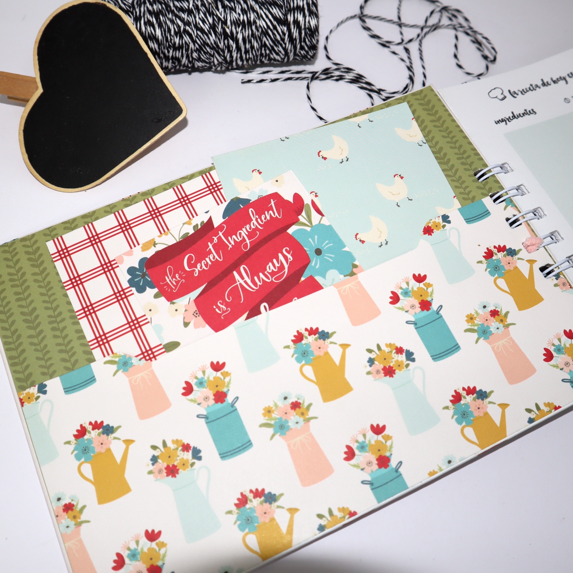 Caderno decorado aberto com padrão de regadores floridos e cartão vermelho com texto